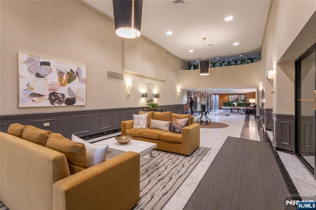 lobby with a high ceiling, wainscoting, and recessed lighting
