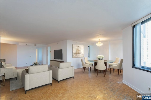 living area featuring plenty of natural light, baseboards, and a chandelier