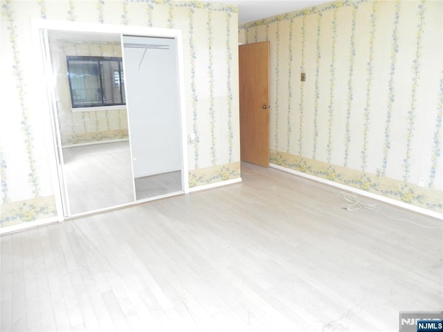 unfurnished bedroom with wood finished floors, a premium fireplace, and wallpapered walls