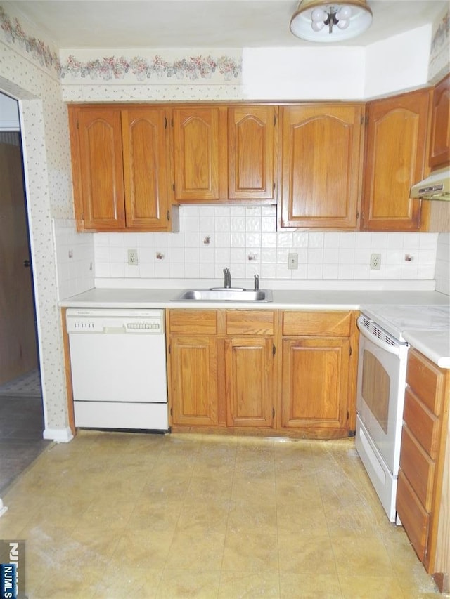 kitchen featuring light countertops, a sink, white appliances, under cabinet range hood, and wallpapered walls