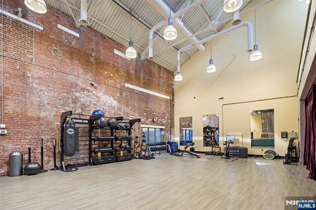 exercise room featuring a towering ceiling and wood finished floors
