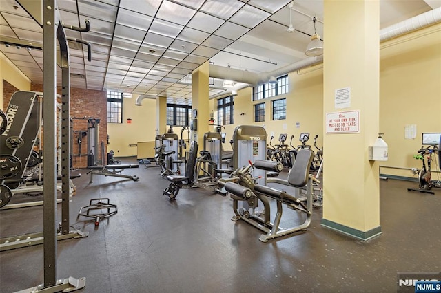 workout area featuring plenty of natural light, a towering ceiling, and baseboards