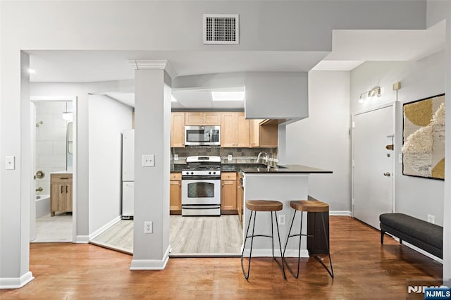 kitchen featuring dark countertops, visible vents, backsplash, appliances with stainless steel finishes, and light wood-style floors
