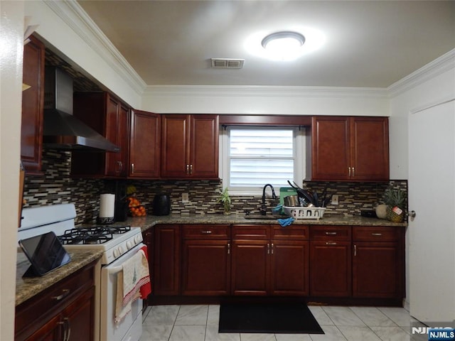 kitchen featuring white range with gas cooktop, ornamental molding, reddish brown cabinets, wall chimney range hood, and backsplash