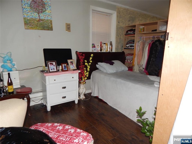 bedroom with a closet, vaulted ceiling, and wood finished floors