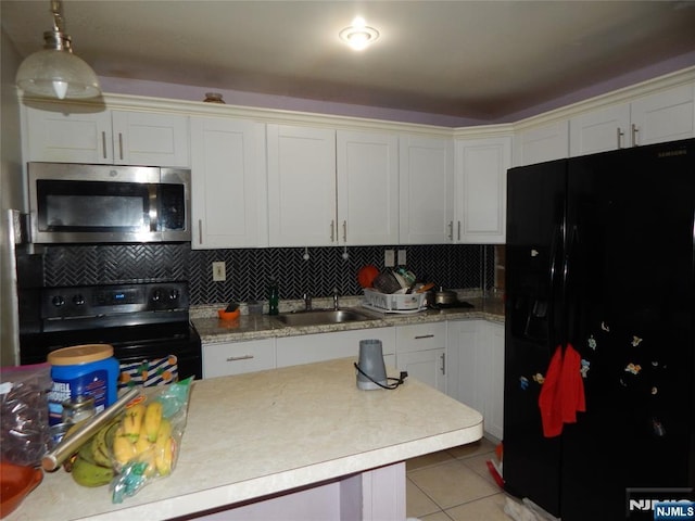 kitchen with light tile patterned flooring, a sink, black appliances, light countertops, and backsplash