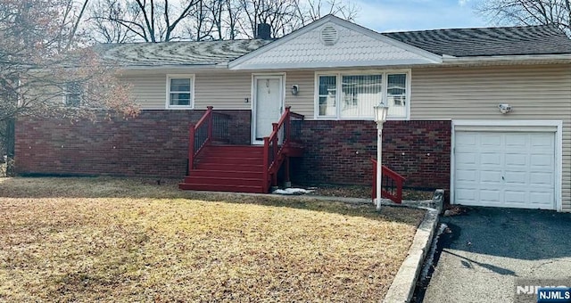 ranch-style house featuring a garage, a front yard, brick siding, and a chimney