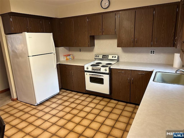 kitchen with white appliances, light countertops, a sink, and dark brown cabinets