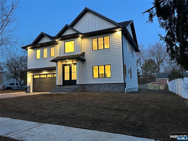 view of front of property featuring driveway, an attached garage, board and batten siding, and fence