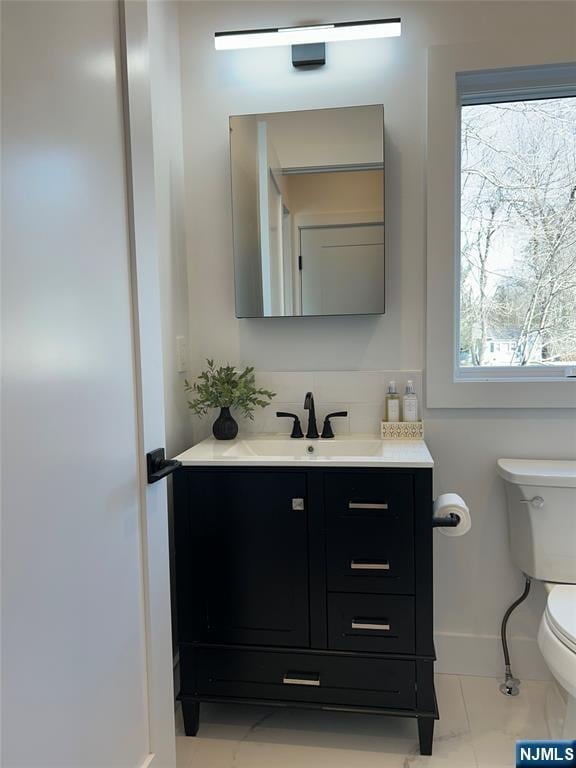 half bath with vanity, toilet, and baseboards