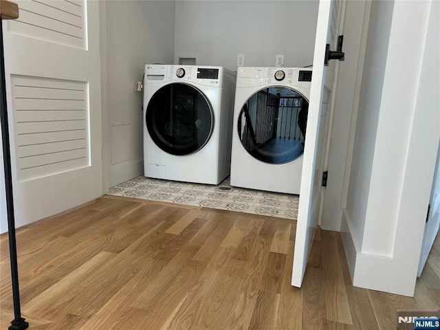 laundry area featuring washer and clothes dryer, laundry area, and light wood-type flooring