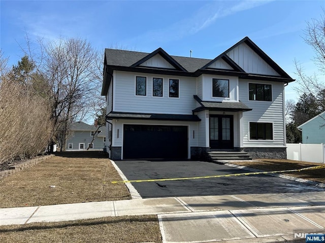 modern farmhouse with aphalt driveway, fence, french doors, board and batten siding, and an attached garage