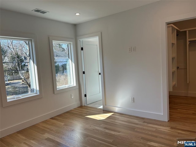 unfurnished bedroom with visible vents, baseboards, wood finished floors, and a spacious closet