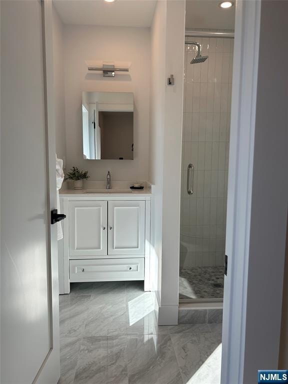 full bath with vanity, marble finish floor, and a stall shower