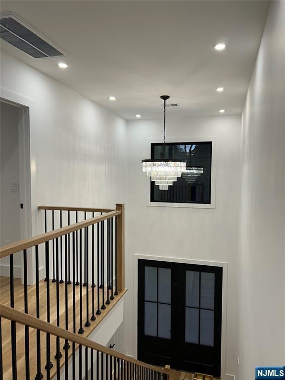 stairway with a notable chandelier, recessed lighting, visible vents, and wood finished floors