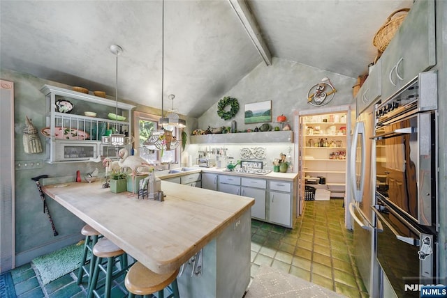 kitchen featuring vaulted ceiling with beams, a peninsula, stainless steel appliances, hanging light fixtures, and open shelves