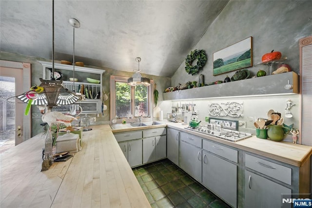 kitchen with white gas stovetop, a sink, wood counters, vaulted ceiling, and hanging light fixtures