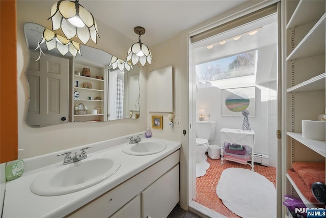 bathroom with a baseboard heating unit, double vanity, a sink, and toilet