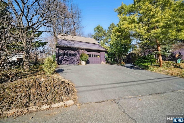 view of side of property featuring an attached garage and aphalt driveway