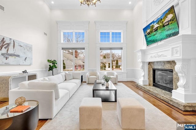 living area with a towering ceiling, a fireplace, ornamental molding, and wood finished floors