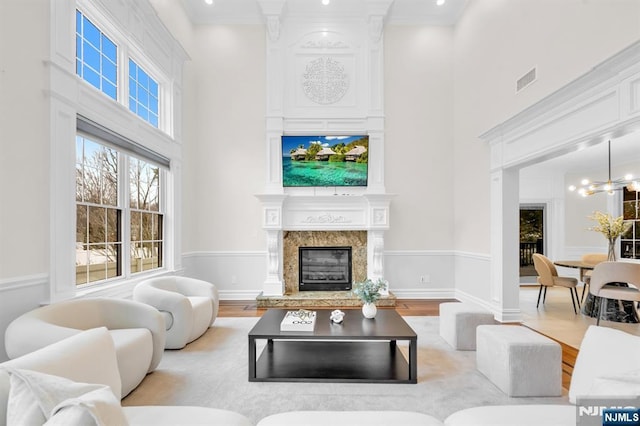 living room featuring visible vents, wood finished floors, a high ceiling, a fireplace, and a notable chandelier