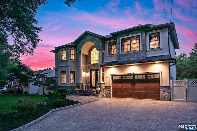 view of front of property with a garage, stone siding, decorative driveway, and stucco siding