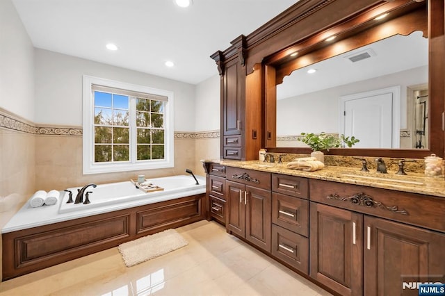 bathroom with double vanity, visible vents, a sink, a bath, and recessed lighting