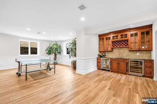 bar with wine cooler, light wood-style flooring, visible vents, and wet bar