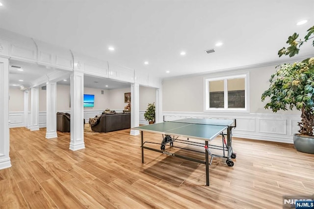 game room with visible vents, decorative columns, a decorative wall, and light wood finished floors