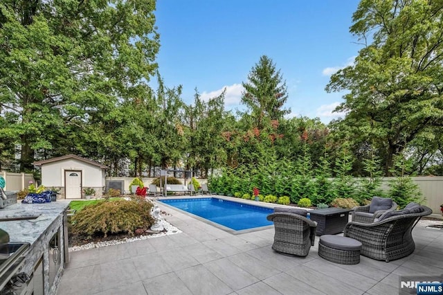 pool with a fenced backyard, an outdoor structure, and a patio