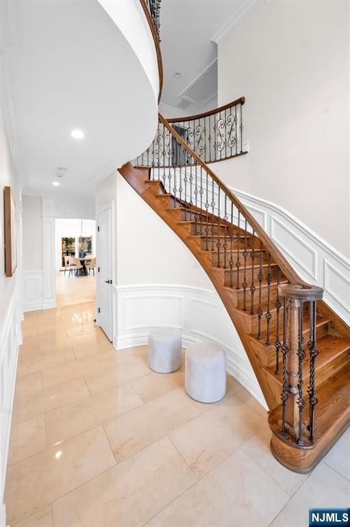 staircase with ornamental molding, recessed lighting, and a decorative wall