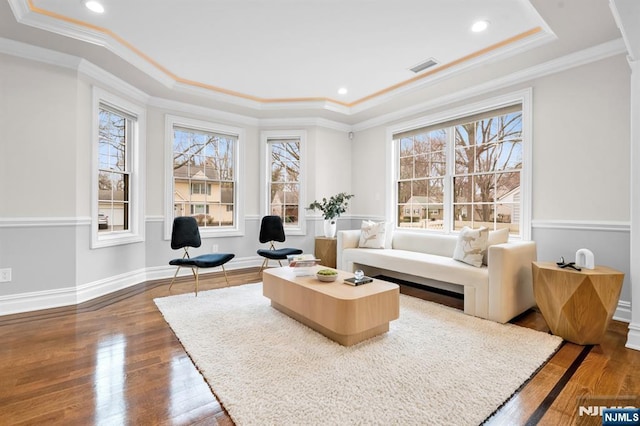 sitting room with a raised ceiling, visible vents, and wood finished floors