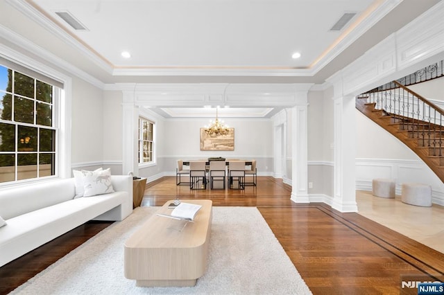 living area with visible vents, a tray ceiling, and decorative columns