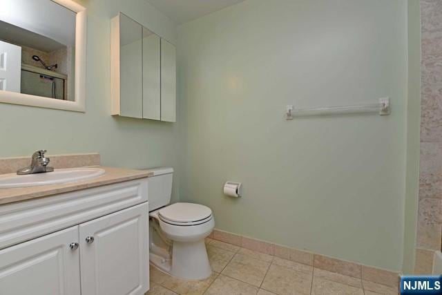 full bath with tile patterned flooring, baseboards, walk in shower, toilet, and vanity