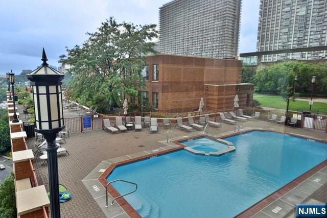 view of pool with a patio and a pool with connected hot tub