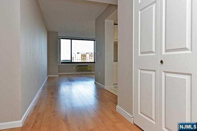 hall featuring light wood-type flooring and baseboards