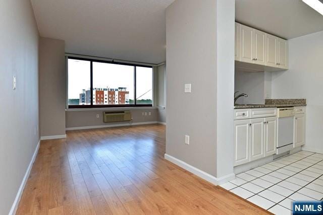 kitchen with baseboards, light wood-style floors, white dishwasher, white cabinetry, and a sink