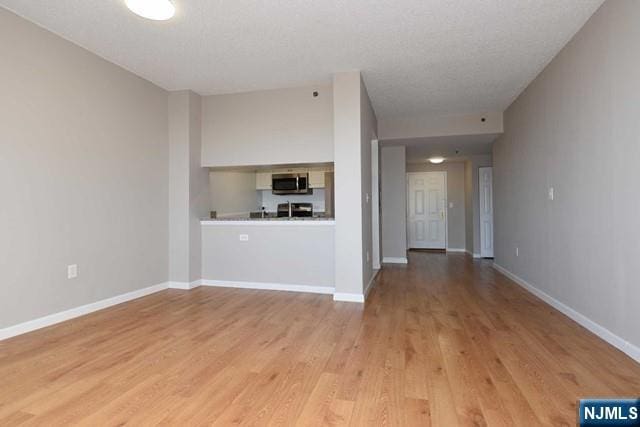 unfurnished living room with light wood-style flooring and baseboards