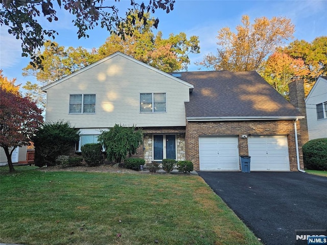 view of front of home with brick siding, a front lawn, aphalt driveway, roof with shingles, and a garage