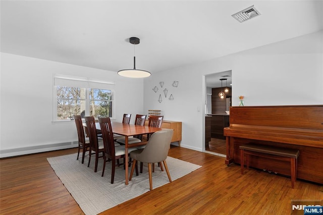 dining space featuring visible vents, baseboard heating, baseboards, and wood finished floors