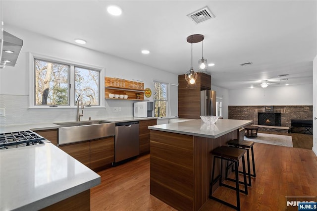 kitchen with visible vents, modern cabinets, a sink, appliances with stainless steel finishes, and a fireplace