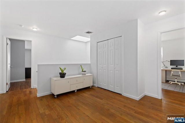 interior space with a skylight, baseboards, and hardwood / wood-style floors