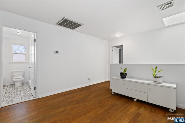 interior space featuring a skylight, wood finished floors, and visible vents