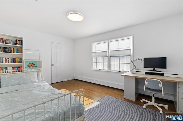 bedroom featuring a baseboard radiator, baseboards, and wood finished floors