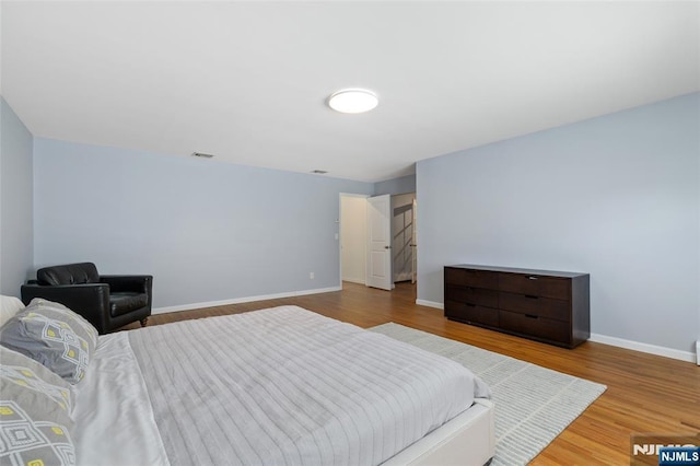 bedroom with visible vents, baseboards, and wood finished floors