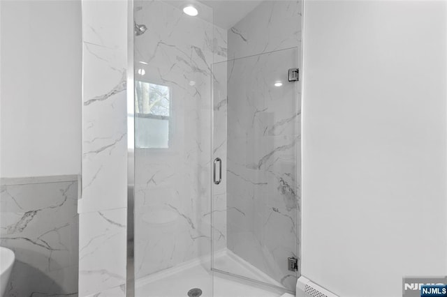 bathroom with a marble finish shower and tile walls