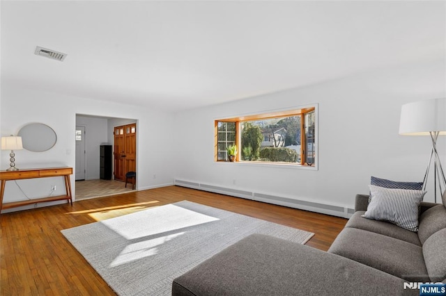 living area featuring wood finished floors, visible vents, baseboard heating, and baseboards