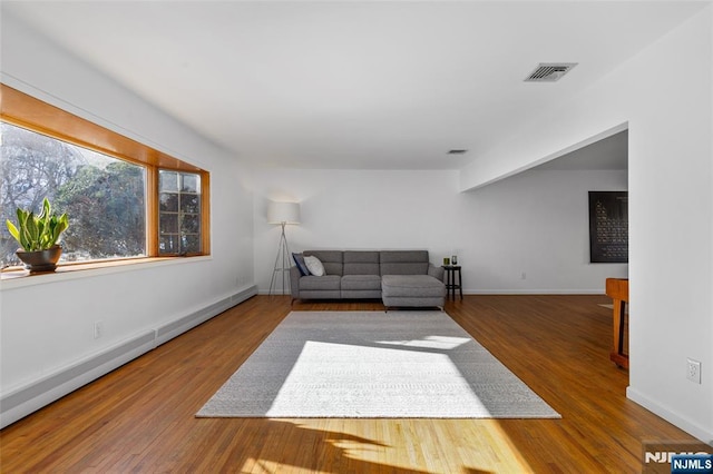 living room with a baseboard heating unit, baseboards, visible vents, and wood finished floors