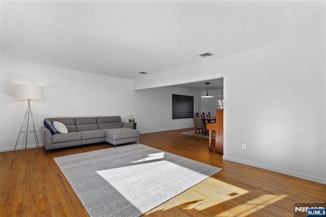 living area with visible vents, wood finished floors, and baseboards