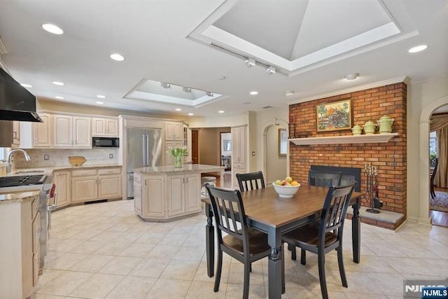 dining area with light tile patterned floors, recessed lighting, a fireplace, and a raised ceiling